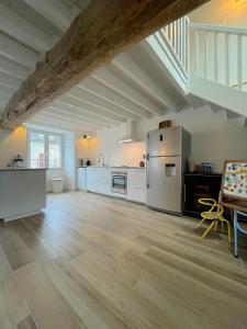 een grote keuken met witte apparatuur en een houten vloer bij Maison bord de mer ・La côtière・ in Piriac-sur-Mer