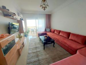 sala de estar con sofá rojo y TV en Rosewood, un appartement de rêve à Asilah Marina Golf en Asilah