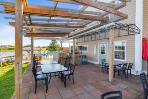 eine Terrasse mit Tischen und Stühlen unter einer hölzernen Pergola in der Unterkunft Inn at the Pier in Cavendish