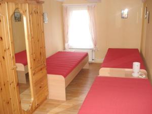 two beds in a room with red sheets and a window at Maria Ferienhaus in Wernigerode
