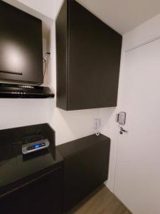 una pequeña cocina con armarios negros y microondas en Apartamento Premium em Pinheiros, en São Paulo