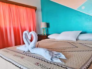 two swans towels are sitting on a bed at Los Delfines Hotel & Dive Center in Little Corn Island