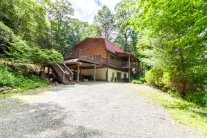 a house in the woods with a gravel driveway at Riverside Retreat in Boone