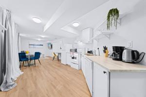 a kitchen with white cabinets and a table with blue chairs at Adorable 1-bdrm basement, Fast WIFI, Free Parking, Smart TV in Barrie