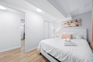 a white bedroom with a bed and a large mirror at Adorable 1-bdrm basement, Fast WIFI, Free Parking, Smart TV in Barrie