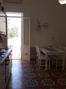 une cuisine avec une table et des chaises blanches ainsi qu'une porte dans l'établissement Signora Minù Bilocale Semindipendente, à Lecce