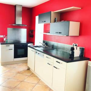 uma cozinha com paredes vermelhas e armários brancos em La Magnanerie *** em Vesseaux