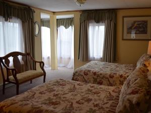 1 dormitorio con 2 camas, silla y ventanas en The Bavarian Manor Hotel, en Purling