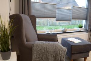 ein Wohnzimmer mit einem Stuhl und einem Fenster in der Unterkunft Privatzimmer im Einfamilienhaus in Emden