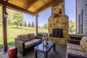 a patio with couches and a stone fireplace at The Retreat at Mountain Meadows in Banner Elk