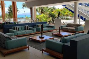 a lobby with blue couches and tables and the ocean at Parfum des îles - vue mer, plage à 30m et piscine en option in Le Gosier