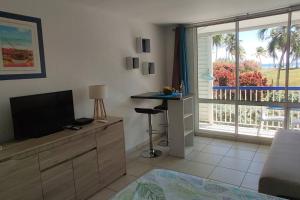 a living room with a television and a large window at Parfum des îles - vue mer, plage à 30m et piscine en option in Le Gosier