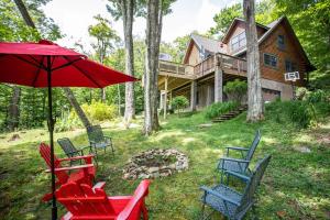 a group of chairs and an umbrella in front of a house at Tree Top Lodge in Sugar Mountain