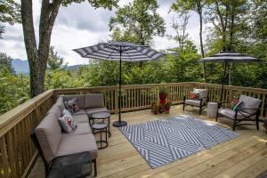 a deck with a couch and chairs and an umbrella at Tree Top Lodge in Sugar Mountain