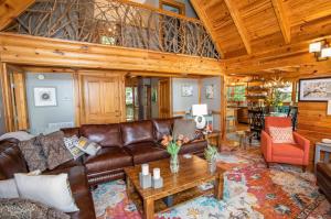 a living room with a leather couch and a table at Tree Top Lodge in Sugar Mountain