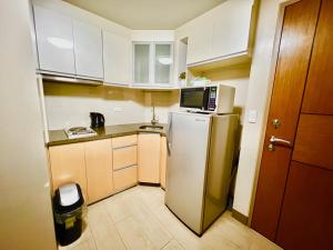 a small kitchen with a refrigerator and a microwave at Cozy condo near Airport Manila in Manila