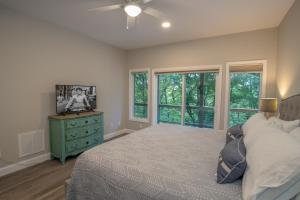 Schlafzimmer mit einem Bett, einer Kommode und Fenstern in der Unterkunft Vistas at Trout Lake in Blowing Rock