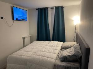 1 dormitorio con 1 cama y TV en la pared en Moderne appart JO avec parking, en Saint-Gratien