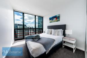 Melbourne Private Apartments - Collins Street Waterfront, Docklands في ملبورن: غرفة نوم بسرير كبير ونافذة كبيرة