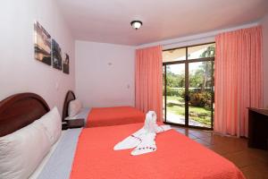 a hotel room with two beds and a large window at Hotel Terraza del Pacifico in Jacó