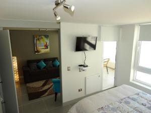 a bedroom with a bed and a flat screen tv on the wall at Laguna del Mar Suites in La Serena