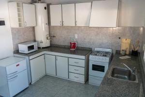 cocina con armarios blancos, fogones y fregadero en Amplio, Verde y Privado. en Mendoza