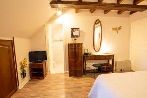 een slaapkamer met een bed, een spiegel en een bureau bij Les Jardins de Virginie in Archignac