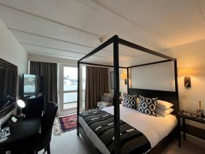 a bedroom with a canopy bed with a desk and a window at Hotel Wroxham in Wroxham