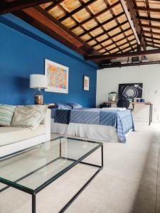 ein Wohnzimmer mit einem Bett und einem Glastisch in der Unterkunft Casa Azul Hibisco - Geriba Buzios in Búzios
