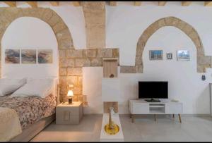 a bedroom with two arches and a bed and a television at LA CASA DEI CANDELAI in Siracusa