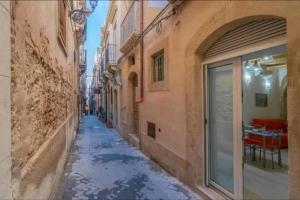 an alley with snow on the ground in a city at LA CASA DEI CANDELAI in Siracusa