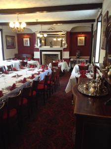 a dining room with tables and chairs and a fireplace at The Crown Hotel in Mundford