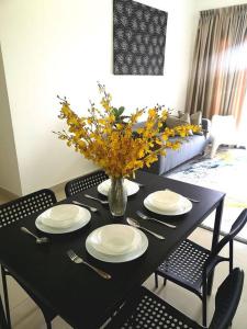 un tavolo nero con piatti e un vaso di fiori di Free Netflix&WiFi Putrizarreth Skyhouse Kt Town a Kuala Terengganu