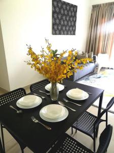 a black table with plates and a vase of flowers at Free Netflix&WiFi Putrizarreth Skyhouse Kt Town in Kuala Terengganu