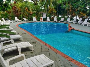 a large swimming pool with white lounge chairs and chairs at La Baula Lodge in Tortuguero