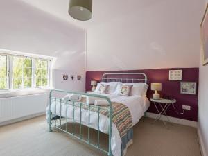 バーリーにあるMast Cottageの紫色のアクセントの壁のベッド1台が備わるベッドルーム1室が備わります。