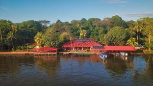 a building with a red roof on a body of water at La Baula Lodge in Tortuguero