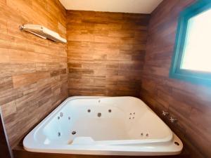 y baño con bañera y paredes de madera. en Rancho La Mesa, 