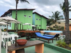 un edificio verde con sillas y piscina en Ap 1122 Village Taperapuã, en Porto Seguro