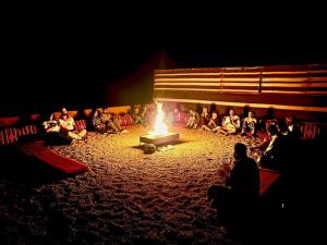 a group of people sitting around a fire at Wadi Rum Desert Camp in Wadi Rum