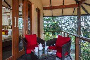 Un balcón con 2 sillas y una mesa con almohadas rojas. en SaffronStays Courtyard, Nashik - infinity pool villa with a huge party lawn, en Nashik
