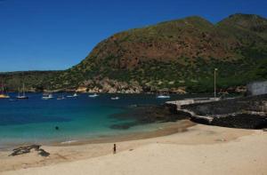 una persona parada en una playa con barcos en el agua en Self-catering Apartment w/ Terrace, en Tarrafal