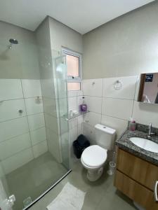 a bathroom with a shower and a toilet and a sink at Condomínio Villamares in Luis Correia
