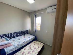 a small bedroom with a bed and a window at Condomínio Villamares in Luis Correia