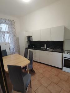 una cocina con armarios blancos y una mesa con sillas. en Central City Apartment, en Viena