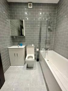 a bathroom with a toilet and a tub and a sink at Alarabi Apartments-Peckham in London