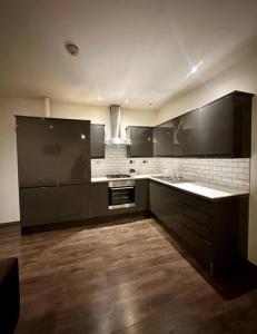 a large kitchen with black cabinets and wooden floors at Alarabi Apartments-Peckham in London