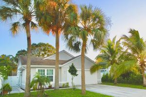 a white house with palm trees in front of it at Jupiter Sunshine in Jupiter