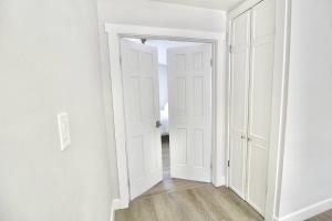 an open door in a room with white walls and wooden floors at Jupiter Sunshine in Jupiter