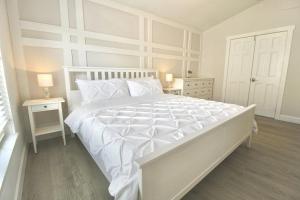 a white bedroom with a large white bed and two tables at Jupiter Sunshine in Jupiter +21 photos